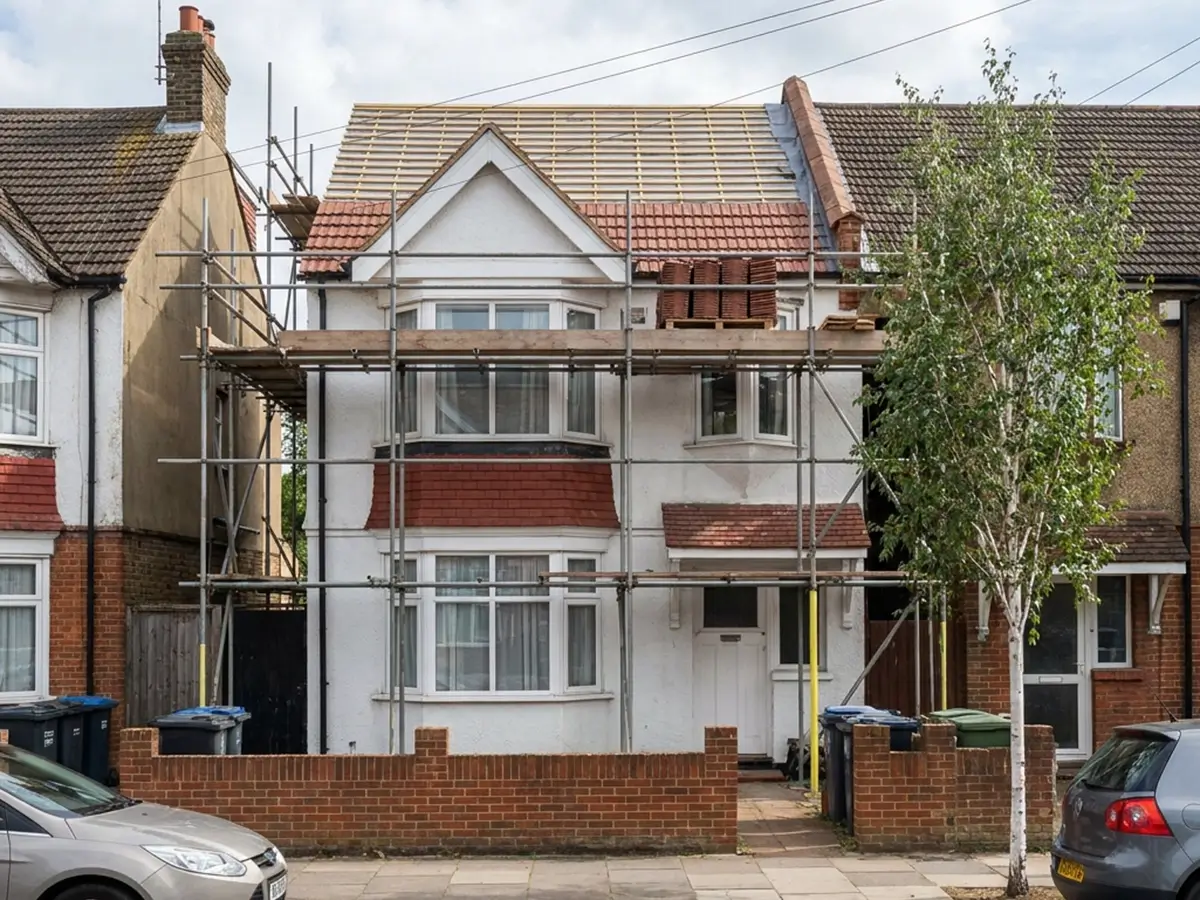 Scaffolded house with its clay tile roof part-way through re-tiling